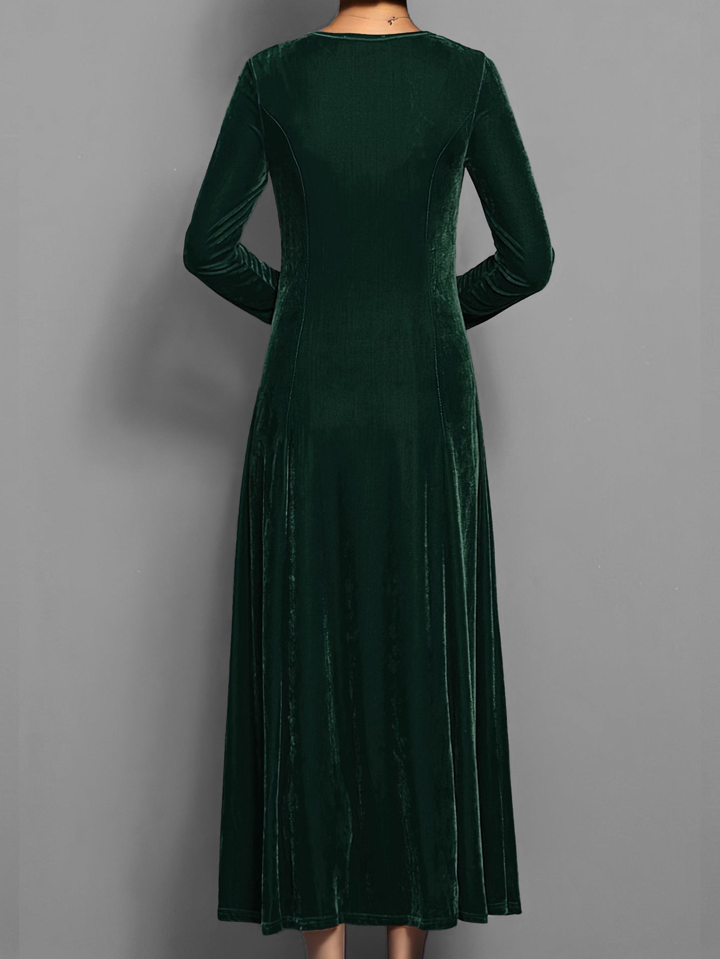 Green - A woman wearing a long sleeve, A-line velvet maxi dress with vertical panelled seams.