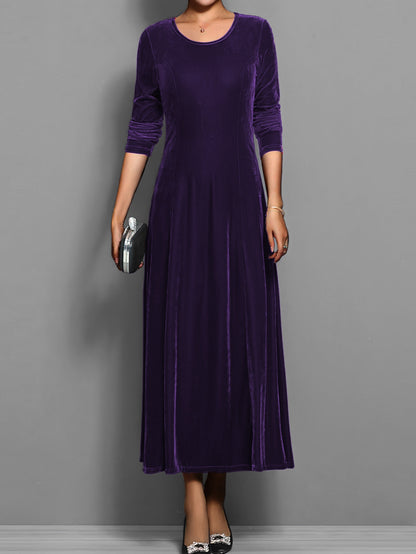 Purple - A woman wearing a long sleeve, A-line velvet maxi dress with vertical panelled seams.