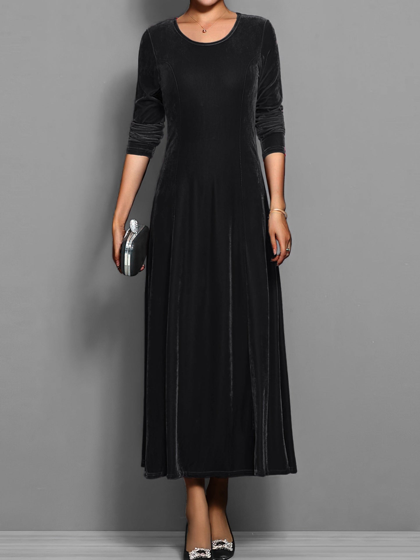 Black - A woman wearing a long sleeve, A-line velvet maxi dress with vertical panelled seams.