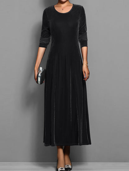 Black - A woman wearing a long sleeve, A-line velvet maxi dress with vertical panelled seams.