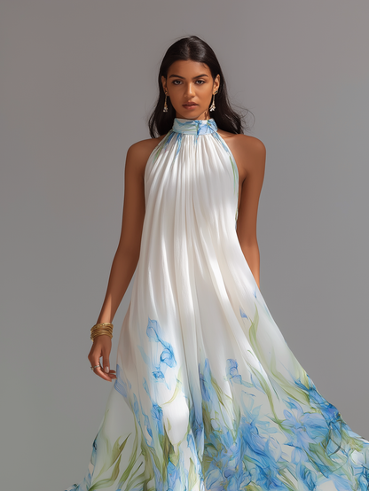 White Printed - A model wears a sleeveless, high halter neck maxi dress made of flowing white chiffon with a blue and green watercolour floral print cascading down the voluminous skirt.