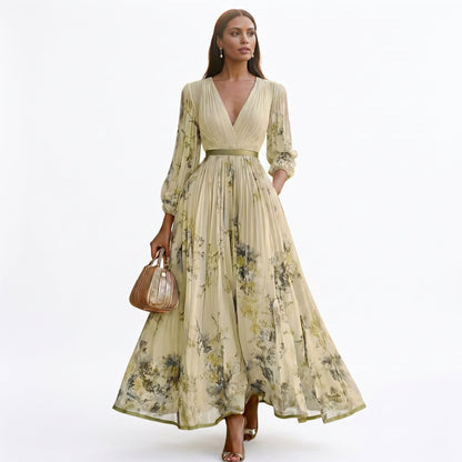 Yellow - A woman wearing a light blue long-sleeve maxi dress with a deep V-neck, pleated bodice and skirt, featuring a blue and grey watercolour floral print.