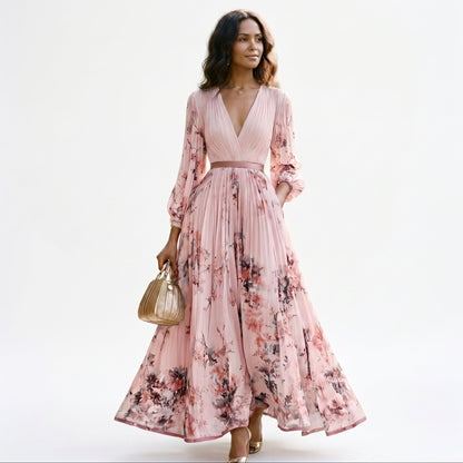 Pink - A woman wearing a light blue long-sleeve maxi dress with a deep V-neck, pleated bodice and skirt, featuring a blue and grey watercolour floral print.