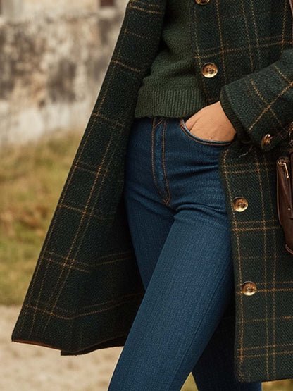 Green - A woman wearing a dark green windowpane check mid-length coat over a forest green turtleneck sweater and blue jeans, carrying a brown leather shoulder bag.