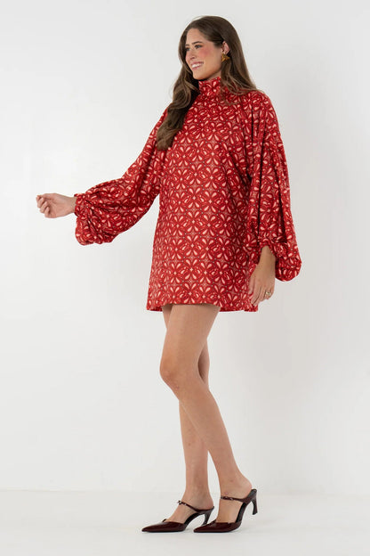 Red - Model wearing a patterned woven mini dress featuring a high neckline, voluminous balloon sleeves, and a relaxed shift silhouette, styled with western boots and holding an acoustic guitar